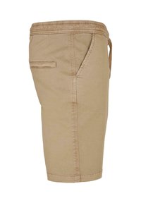 Short beige longueur genou avec taille élastique, poches latérales fendues et poche passepoilée arrière, vu de côté.