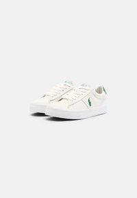 Zapatillas de lona blancas con acentos verdes, con punta redonda, suela de goma plana y diseño de cordones. Incluyen logo de marca en el lado.