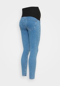 Ljusblåa gravidjeans med svart elastisk midjepanel, bakfickor och slim fit ben mot en vit bakgrund.