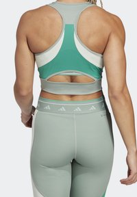 Conjunto de sujetador deportivo y leggings en verde claro con paneles contrastantes en verde oscuro. El sujetador presenta un diseño de espalda racer y detalles con recortes; los leggings tienen una cinturilla elástica.