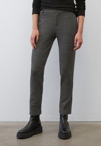 Pantalons à motif chevron gris avec une coupe ajustée, fermeture à bouton sur le devant et poches latérales, associés à des bottines noires à semelles épaisses.