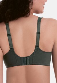 Reggiseno verde scuro con spalline regolabili, dettagli in pizzo e chiusura a gancio e asola sul retro. Tessuto morbido e liscio.