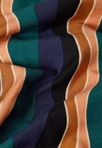 Randig tyg med teal, rost, svart, marinblå och persikofärger. Mjuk textur med olika bredder på ränderna som skapar ett vågigt mönster.