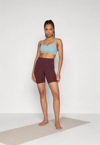 Ανοιχτό μπλε αθλητικό σουτιέν και μπορντό σορτς, εφαρμοστός σχεδιασμός, κατασκευασμένα από ελαστικό υλικό, ομαλή υφή, ελάχιστη σήμανση στα σορτς.