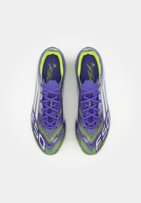 Purple soccer cleats with green accents, featuring a streamlined design, textured surface, and bold "F50" branding on the sides.
