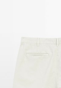 Beige Baumwollhose mit einer Gesäßtasche, geradem Schnitt und Gürtelschlaufen. Glatte Textur mit dezenten Steppdetails.