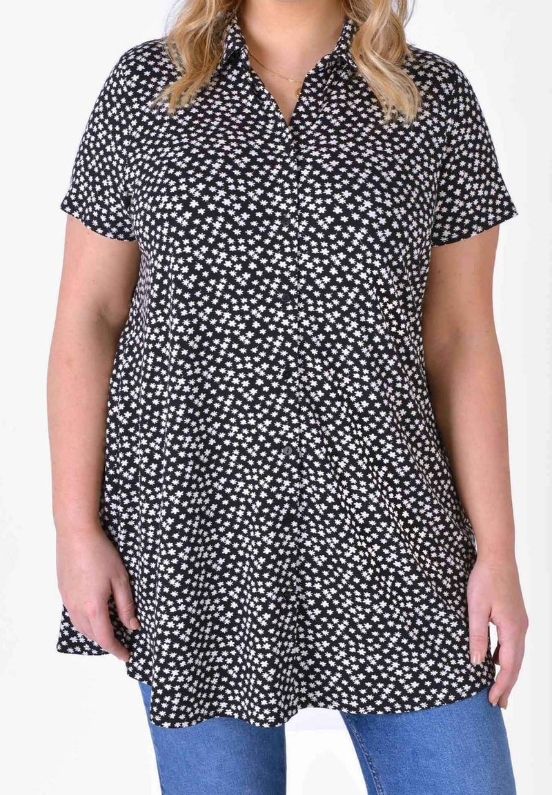 Short-sleeve black shirt featuring a white floral pattern, button front, and curved hem. Soft fabric with a relaxed fit.