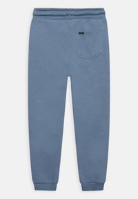 Pantalones de chándal azules hechos de una tela suave con una cinturilla y puños elásticos, que cuentan con un solo bolsillo trasero en el lado derecho.