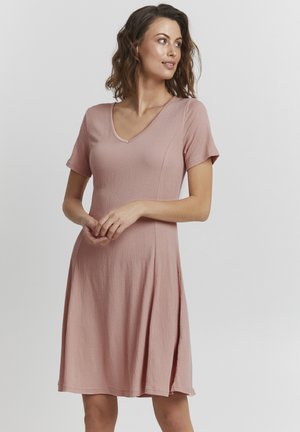 Kortärmad klänning med v-ringning i ljusrosa textil. Smickrande passform med en utsvängd kjol, som har sidoklipp för enkel rörelse.