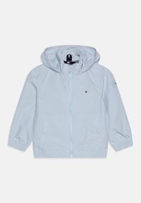 Světlomodrá lehká bunda na zip s kapucí, elastickými manžetami, dvěma bočními kapsami a malým logem na prsou. Hladký nylonový materiál.