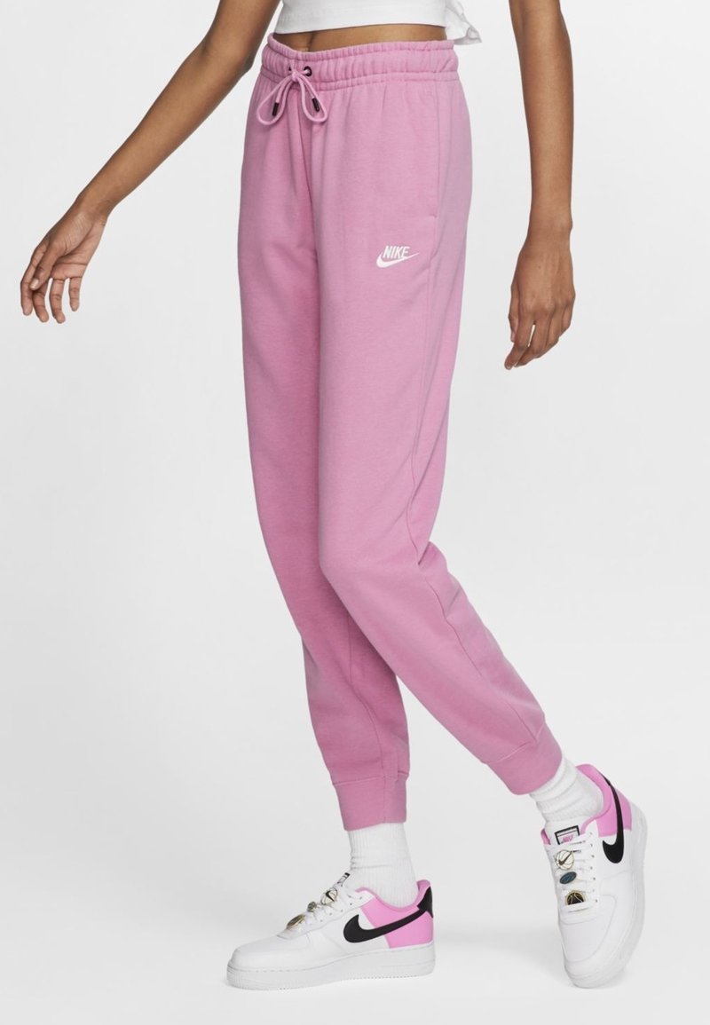 Rosa sweatpants med elastisk midjeband och dragsko, med en vit Nike-logotyp. Tillsammans med vita sneakers med rosa och svarta detaljer.