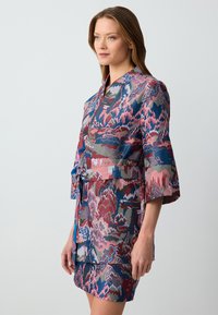 Sukienka z nadrukiem w odcieniach różu, niebieskiego i zielonego z paskiem w talii, rękawami kimono i warstwowym krojem spódnicy.