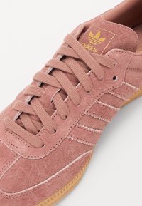 Baskets en suède rose avec dessus texturé, accent de logo doré et semelle extérieure en caoutchouc beige. Caractérisées par un bout arrondi et des lacets plats.