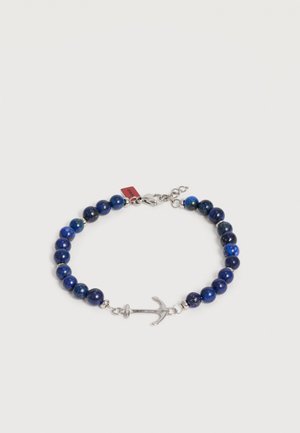 Bracelet avec des perles rondes bleu foncé et un pendentif en forme d'ancre en argent, sécurisé par un fermoir mousqueton avec une chaîne réglable.