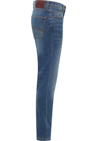 Kék farmer skinny farmernadrág közepes emeléssel, öt zsebbel és barna bőrpárnával a derékon. Simaság jellemzi, testhezálló fazon.