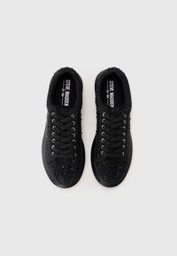 Adidași negri cu un sistem superior texturat și strasuri, vârf rotund, șireturi negre și talpă plată din cauciuc. Eticheta brandului este vizibilă în interior.