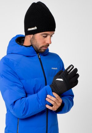 Black gloves with a textured finish and white accents, worn with a blue padded jacket and black knitted hat. Features a snug fit at the wrist.