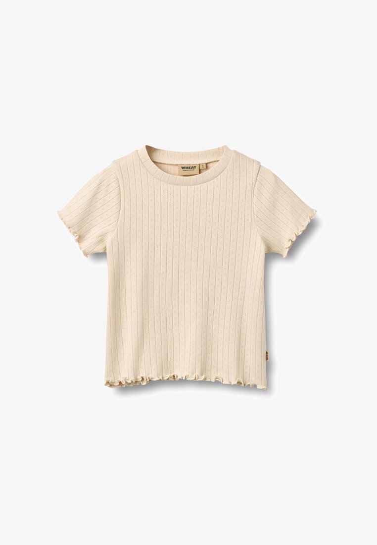 Bézs színű, rövid ujjú, bordázott kötésű kisgyermek póló apró kivágásos részletekkel és fodros szegélyekkel az ujjakon és az alján.