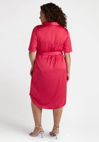 Rosa, knielanges Kleid mit kurzen Ärmeln, tailliertem Design und verstreuten Strassakzenten. Glattes, leichtes Material mit glänzendem Finish.