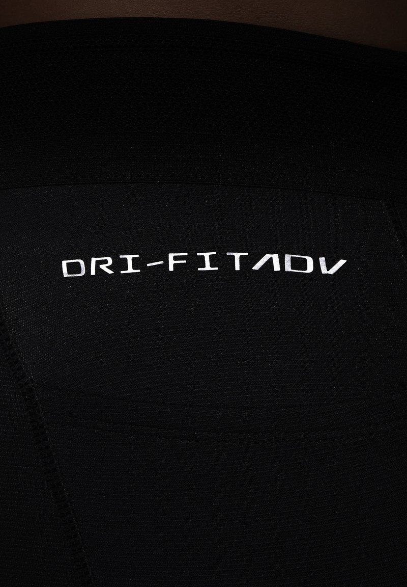 Leggings de sport noirs en tissu texturé, avec un logo blanc "DRI-FIT ADV" dans le dos, mettant en avant un design à la fois élégant et fonctionnel.