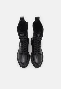 Bottes lace-up en cuir noir avec un orteil arrondi, doublure en peluche et semelle en caoutchouc. Comprend une languette et des coutures contrast�ées.