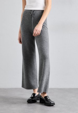 Pantaloni a gamba larga grigi in maglia con vita regolabile, caratterizzati da una consistenza morbida e una vestibilità relaxed, abbinati a mocassini neri con plateau.