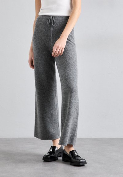 Pantaloni largi gri tricotati cu talie ajustabila, avand o textura moale si o croiala lejera, asociați cu loafers negri cu platformă.