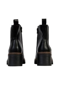 Bottines en cuir noir avec une texture lisse, des zips sur les côtés et un talon empilé. Présente un détail de couture beige le long de la semelle.