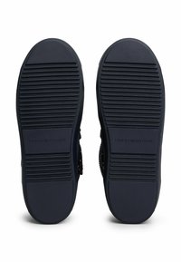 Suole di scarpe in gomma navy con texture rigata e un logo, caratterizzate da un bordo esterno liscio e accenti intrecciati a contrasto sui lati.