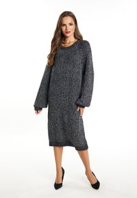 Abito maglione oversize nero e grigio con maniche lunghe, scollo rotondo e vestibilità ampia, caratterizzato da polsini e bordo a costine.