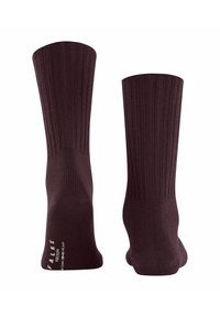 Para ciemno-brązowych skarpetek z prążkami pokazanych od tyłu, z białym napisem marki blisko pięty na jednej skarpetce.