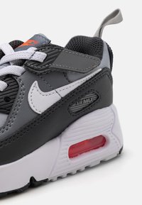 Nike Air Max sportcipő fekete és szürke szintetikus felsőrésszel, fehér részletekkel, rózsaszín légkamrával és texturált hálós nyakkal a légáteresztés érdekében.
