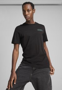 Sort bomulds T-shirt med korte ærmer og rund hals, prydet med et lille turkist Puma-logo på venstre bryst.