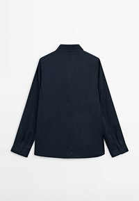 Chemise à manches longues bleu marine foncé avec un col, des poignets à boutons et une texture lisse ; présente une couture de empiècement dans le dos pour la forme.