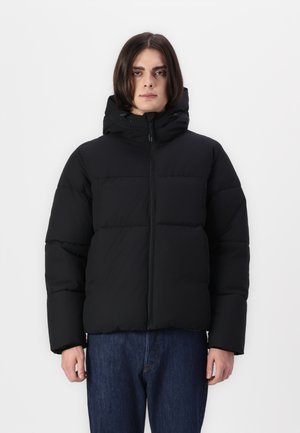Black puffer jacket with a hood, featuring a zip front, horizontal seams, and a thick, insulated design. Worn over blue jeans.