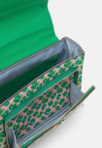 Zelená látková kabelka s texturovaným povrchem, uvnitř růžová s zelenými květinovými vzory a několika přihrádkami. Zlacený zip.