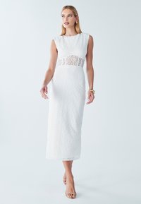 Robe midi en dentelle blanche avec un corsage ajusté, des manches courtes, et un panneau en dentelle transparente à la taille, offrant une finition lisse et texturée.