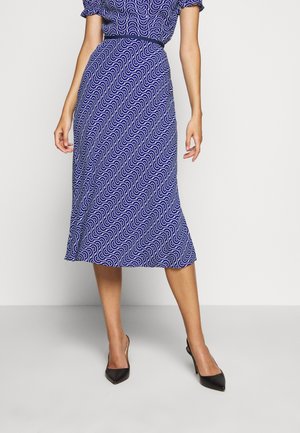 Navy blue midi dress with white wave pattern, short sleeve, cinched waist, flowing skirt, paired with black pointed-toe heels.