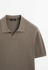 Polo marron tricoté à manches courtes avec col côtelé et encolure dégagée, vue à plat sur fond blanc.