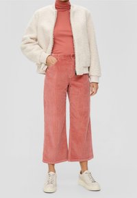 Fuzzy off-white bomber jacket, fitted pink turtleneck, wide-leg pink corduroy pants, and light beige sneakers. Soft textures and contrasting colors.