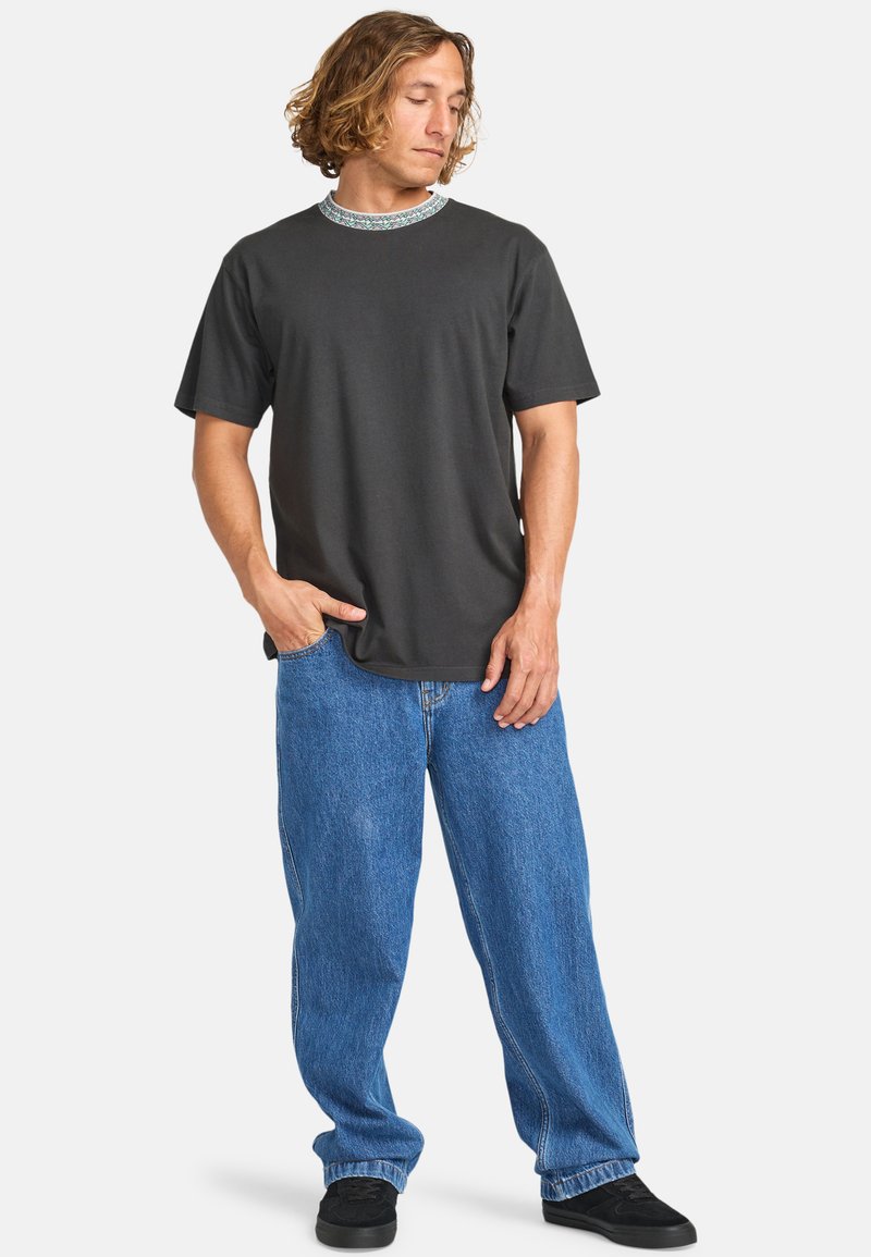 Dark gray cotton t-shirt with a patterned collar, paired with light blue baggy jeans and black sneakers. Simple, relaxed fit design.