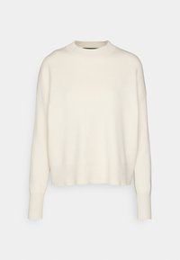 Krämfärgad stickad tröja med hög krage, nedtonade axlar och avslappnad passform. Har långa ärmar och ribbad nederkant.