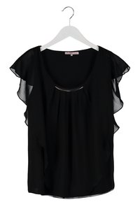 Blouse noire à manches courtes avec manches à volants transparentes, encolure ronde, et détail en métal argenté, présentée sur un cintre blanc.