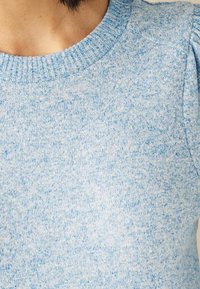 Pull en laine bleu clair avec un motif texturé et un col côtelé. Présente des épaules bouffantes pour un détail de design supplémentaire.