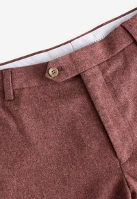 Braune strukturierte Hose mit einem einzelnen Knopfverschluss am Bund. Der Stoff hat ein dezentes Muster und ein glattes Innenfutter.