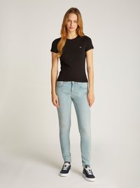 Black short-sleeve fitted t-shirt, light blue skinny jeans, and dark sneakers with white soles. Simple design, smooth fabric texture.