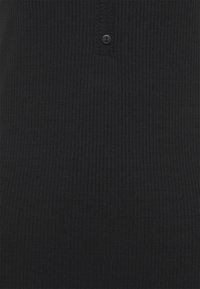 Tissu côtelé noir avec deux petits boutons noirs près du centre supérieur, montrant un gros plan sur la texture et les détails de la couture.