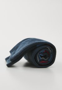Chaussettes roulées bleues avec une texture lisse, présentant des coutures contrastantes en rouge, bleu et gris. Forme compacte sur un fond clair.