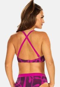 Fioletowy i różowy stanik bikini w kamuflażowy wzór z krzyżującymi się ramiączkami i zapięciem na hak z tyłu, wykonany z gładkiego, elastycznego materiału.