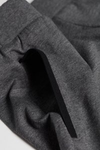 Graue Stoffshorts mit elastischem Bund und schwarzem Innenband. Weiche Textur mit feiner Stoffstruktur und leichten Falten.
